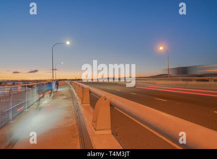 Tauranga Harbour Bridge di percorso di trasporto con il trasporto su strada e il percorso ciclo-pedonale con candelette di ciclisti e veicolo luci di passaggio Foto Stock