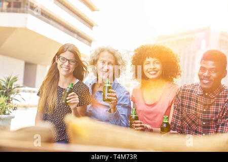 Gruppo multiculturale di amici di bere birra a un partito su un tetto di casa Foto Stock