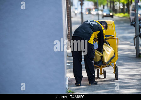 Postbote in der Großstadt zu Fuss unterwegs. Foto Stock