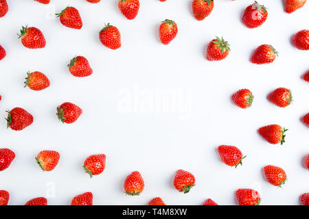 Fragola su sfondo bianco, vista dall'alto. Modello di frutti di bosco. Cornice fatta di fragole fresche su sfondo bianco. Cucina creativa del concetto. Piatto, laici copia s Foto Stock