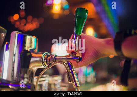 Siamo in grado di soddisfare l'Oktoberfest. Mano del barista versando una grande birra lager in tap. Versare birra per client. Vista laterale del giovane barista versare birra mentre Foto Stock