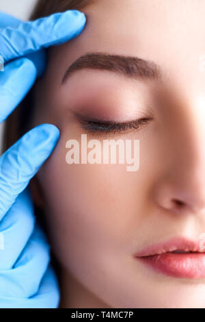 Estetista medico le mani in guanti toccando volto di donna attraente. Moda modello bionda dopo trattamento cosmetico. Cosmetologia estetica, plastica Foto Stock