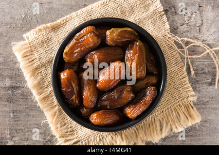 Date in nero ciotola sul tavolo di legno Foto Stock