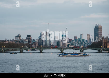 London, Regno Unito - 13 Aprile 2019: Thames Clipper sul Fiume Tamigi, lo skyline di Londra sullo sfondo, durante le ore di colore blu. La Clippers sono il modo più veloce e Foto Stock