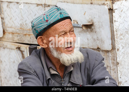 Ritratto di anziani, barbuto Uyghur uomo che indossa un tradizionale doppa (HAT). Catturato in un mercato di Kashgar (provincia dello Xinjiang, Cina) Foto Stock