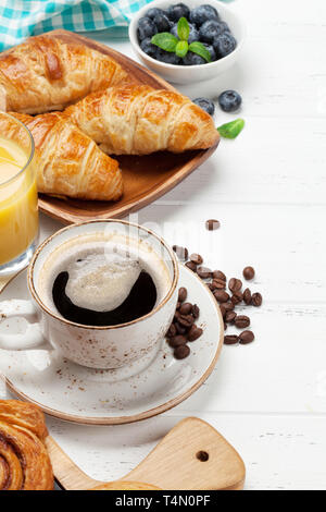 Caffè, cornetti, succo di arancia, panini alla cannella e le bacche di prima colazione. Su un tavolo di legno. Copia con spazio per il testo Foto Stock