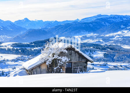 Fienile tradizionale in invernale Algovia superiore con imponenti montagne sullo sfondo Foto Stock