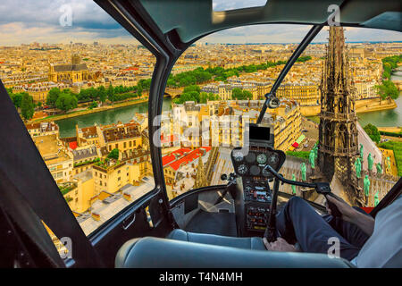 Cockpit in elicottero volando sulla chiesa di Notre Dame con la sua guglia e sulla skyline di Parigi, capitale francese, l'Europa. Volo panoramico su Parigi cityscape. Foto Stock