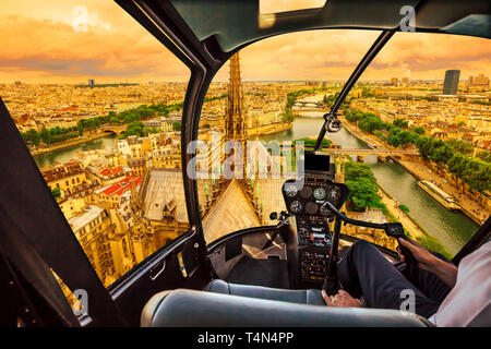 Cockpit in elicottero volando al tramonto sulla Cattedrale di Notre Dame de Paris e sulla skyline di Parigi, capitale francese, l'Europa. Volo panoramico su Parigi Foto Stock