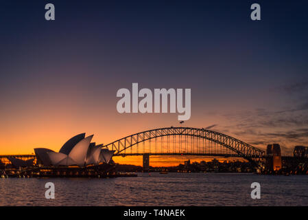 Sydney, Nuovo Galles del Sud / Australia - 17 Maggio 2016: Sydney Opera House illuminato con luce notturna con Harbour Bridge per il diritto e l'ultimo Foto Stock