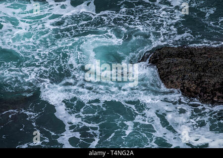 Mare turbinano intorno rocce sulla costa della Cornovaglia, UK. Foto Stock