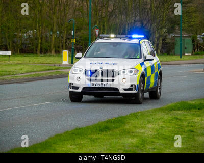 Una BMW pattuglia di polizia a velocità di lampeggio luci blu in un territorio rurale trunk road nel North Yorkshire Foto Stock