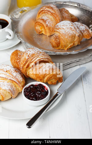 La prima colazione con cornetti, marmellata e caffè sul tavolo in legno Foto Stock