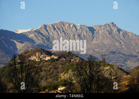 Vista di un piccolo villaggio tipico sulla cima di una collina nel sud della Francia al tramonto dalle montagne Foto Stock