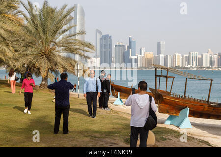 ABU DHABI, Emirati arabi uniti, 10 gennaio 2019: i turisti sono fotografati sulle rive della baia sullo sfondo di una vecchia imbarcazione in legno e un bel panorama o Foto Stock