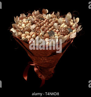 Bouquet unico costituito da diversi tipi di dadi, decorato con foglie, coni e rametti. Vista laterale su sfondo nero Foto Stock