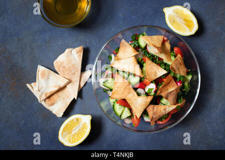 Fattoush tradizionale insalata di verdure e pane pita. Levantine, arabo, cucina medio-orientale. Servita in una lastra di vetro con il limone, pita e ol Foto Stock