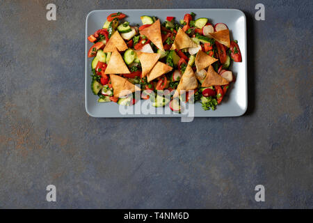 Fattoush tradizionale insalata di verdure e pane pita. Levantine, arabo, cucina medio-orientale. Servita in una piastra rettangolare. Sfondo scuro. Foto Stock