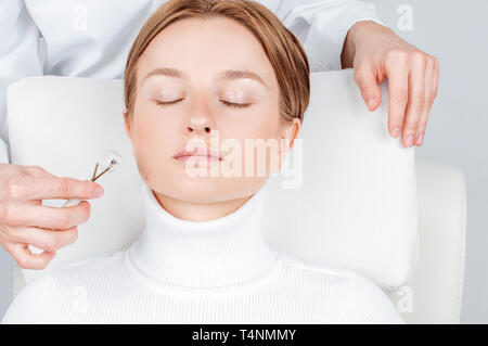 Bella donna avente la bellezza del viso Trattamento, cosmetologo il massaggio viso con rulli di giada. Foto Stock