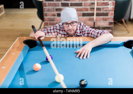 Hipster guy preparando per il prossimo colpo da biliardo. Foto Stock