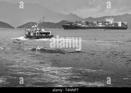 Foto in bianco e nero della nave portacontainer KOTA LUKIS, lascia i terminali per container Kwai Tsing a Hong Kong e si dirige verso il canale Lamma orientale Foto Stock