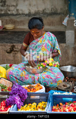 Vista verticale di una donna in un duro lavoro rendendo ghirlande a Mattuthavani mercato dei fiori a Madurai, India. Foto Stock