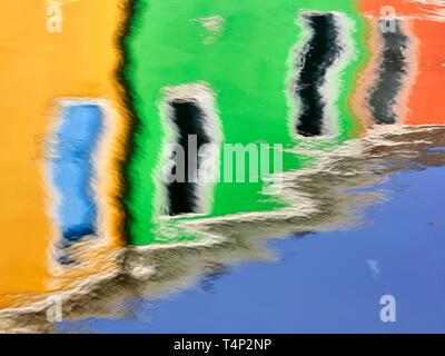 Facciate colorate riflessi nell'acqua di un canale, Burano, Venezia, Veneto, Italia Foto Stock