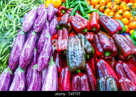Verdure fresche, tra cui melanzane a righe e peperoni rossi in mostra in un mercato locale in Spagna Foto Stock