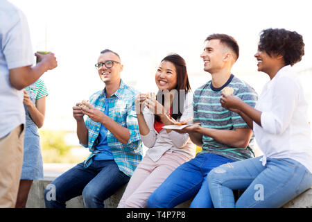 Persone, di amicizia e di concetto internazionale - gruppo di felice gli amici a bere succo di frutta, mangiare pizza e tramezzini e parlando in posizione di parcheggio Foto Stock