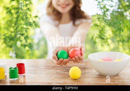 Pasqua, vacanze e concetto di persone - close up della ragazza in mani tenendo le uova colorate di verde su sfondo naturale Foto Stock