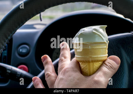 Uomo con gelato al volante di una vettura Foto Stock