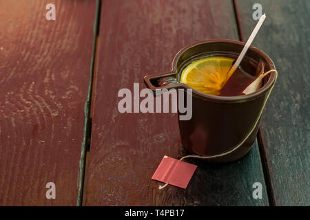 La coppa di plastica con tè e limone sul legno vecchio tavolo Foto Stock