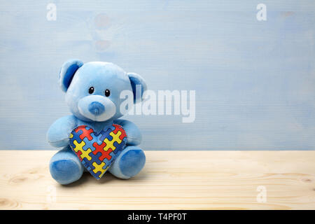 Mondo autismo giornata di sensibilizzazione, concetto con Teddy bear holding o puzzle jigsaw pattern sul cuore Foto Stock