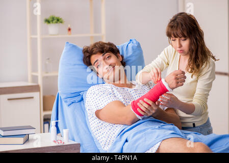 Amorevole moglie guardando dopo aver ferito il marito in ospedale Foto Stock