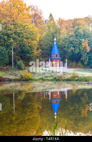 Una piccola chiesa sulla riva di un lago in autunno foresta di riserva Tovtry, Khmelnitsky regione, Ucraina. Foto Stock