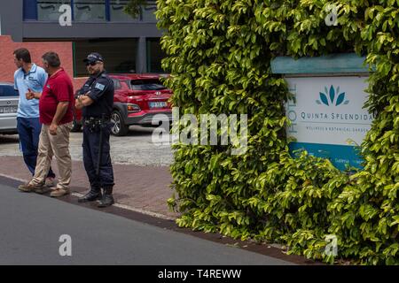 A Canico, Portogallo. Xviii Apr, 2019. Di fronte all'hotel 'Quinta Splendida' indica un poliziotto accanto a due uomini. Qui i passeggeri di un autobus del bus incidente sono stati alloggiati in cui 29 morti su 17.04.2019 sull'Atlantico portoghese isola di Madeira. In base alle precedenti conclusioni, probabilmente ci sono molti turisti tedeschi tra le vittime. Credito: Frank Zagel/dpa/Alamy Live News Foto Stock