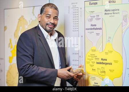 Mauer, Germania. Xvii Apr, 2019. John Ehret, sindaco di Mauer è in piedi accanto a una scheda di informazioni in municipio con la scritta 'Homo Heidelbergensis' con la replica di una ganascia inferiore dell' Homo Heidelbergensis trovati in Mauer nella sabbia Grafenrain pit. Questa ganascia ha un enorme significato per la storia dell'umanità. I fossili trovati in un luogo secco Neckar bow appartiene con i suoi 610 000 anni per i più antichi reperti umani in Europa. (A dpa 'Homo Heidelbergensis - La comunità che i sogni di un museo') Credito: Uwe Anspach/dpa/Alamy Live News Foto Stock