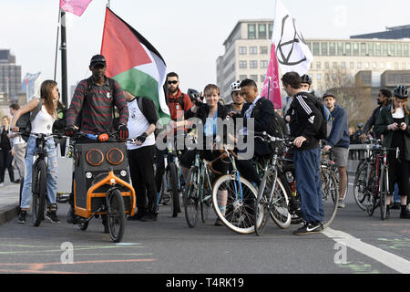 London, Greater London, Regno Unito. Xviii Apr, 2019. Il cambiamento climatico i manifestanti sono visti con un'Estinzione bandiera di ribellione e una bandiera palestinese mentre sono in attesa per la Massa Critica ride per avviare durante la ribellione di estinzione sciopero a Londra.gli ambientalisti dall'Estinzione il movimento di ribellione attesa per il quarto giorno consecutivo Waterloo Bridge di Londra. Gli attivisti è stato parcheggiato un camion sul ponte bloccando la strada causando interruzioni. Di polizia sono stati arresto di manifestanti che si rifiutano di testa a Marble Arch. Estinzione della ribellione esige dal governo azioni dirette Foto Stock