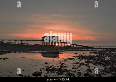 Isola di Roa, Cumbria, Regno Unito. Il 19 aprile 2019. Regno Unito Meteo. Sunrise da Roa Island scialuppa di salvataggio sulla stazione di La costa del Cumbria. Credito : Greenburn / Alamy Live News. Foto Stock