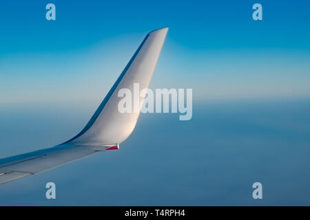 Bella aletta di un aereo, presa dal lato della finestra, durante i viaggi aerei in alta quota con crystal clear atmosfera blu al di fuori della finestra Foto Stock