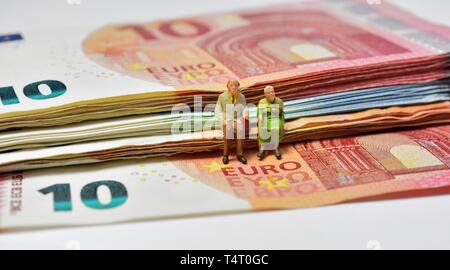 Statuine in miniatura,pensionato giovane, seduti su euro note,moneta, Foto Stock