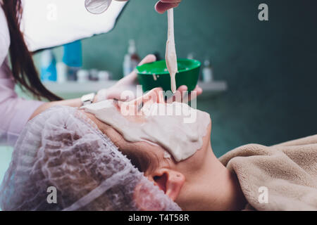 Bella donna avente un cosmetico del viso trattamento scrub da professional dermatologo presso wellness spa. Anti-invecchiamento, la pelle del viso cura e vita di lusso Foto Stock