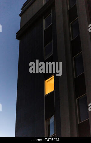 Lonely finestra illuminata in alto edificio di appartamenti. Foto Stock