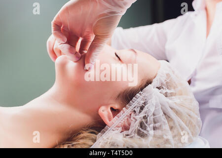 Cosmetologo fa un massaggio boccale del paziente i muscoli facciali Foto Stock