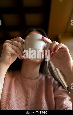 La ragazza beve caffè in un bar. Vista dal basso Foto Stock
