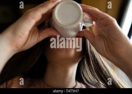 La ragazza beve caffè in un bar. Vista dal basso Foto Stock