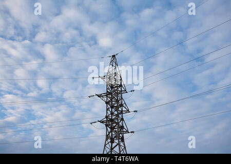 Supporta le linee elettriche ad alta tensione contro il cielo blu con nuvole. Industria elettrica. Foto Stock