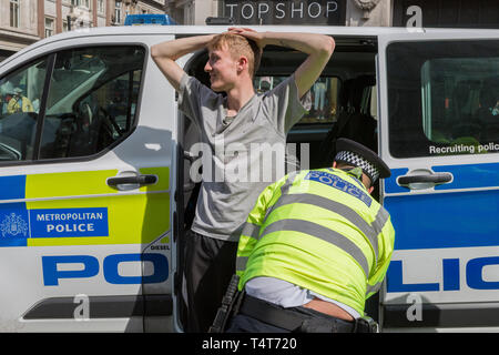 Un giovane manifestante maschio viene arrestato e cercato da ha incontrato funzionari di polizia a Oxford Circus il giorno 4 di proteste da parte del cambiamento climatico attivisti ambientali con il gruppo di pressione la ribellione di estinzione, sul diciottesimo mese di aprile 2019, a Londra, in Inghilterra. Foto Stock
