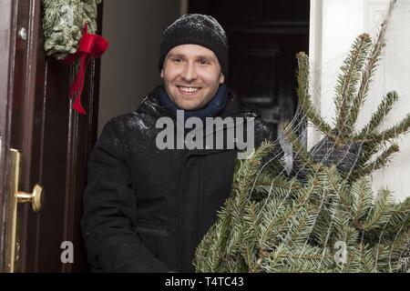 Uomo con un pacchetto di albero di Natale Foto Stock