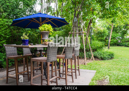 Sedia tavolo con ombrellone blu nel cortile del giardino Foto Stock